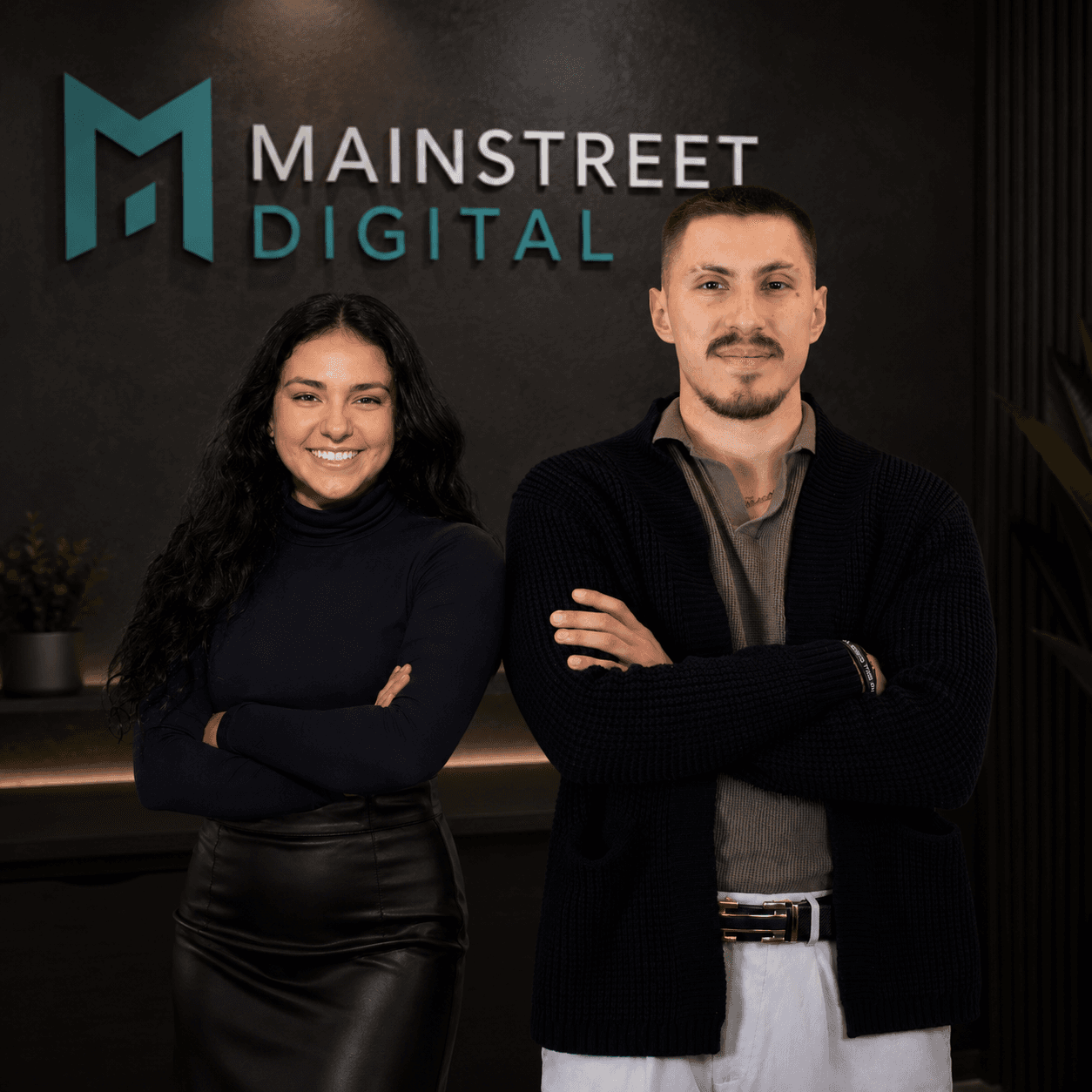 A smiling man and woman standing with arms crossed before a Mainstreet Digital logo.